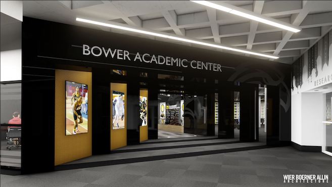 place image at the top, under the heading
Photograph of the entrance of the Bower Academic. At the bottom of the photo, the flooring is gray with black stripes. The entrance angles inward and is black with gold panels on the left featuring images of athletes playing basketball, baseball and football. Over the entrance is the words Bower Academic Center. At the top of the image, the ceiling is light gray with horizontal light fixtures.