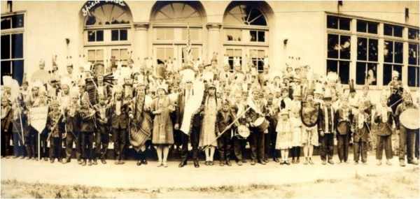 Members of the Go Hawks Tribe founded by childrens literature author Emilie Blackmore Stapp. Many of the members are holding musical instruments.  