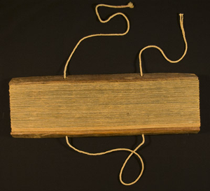 View of palm leaf manuscript from the fore-edge against a black background.  