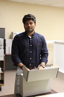 Photograph of Abubaker Zahoor in his office with a box from the collection.