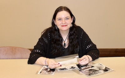 Photo of Emma Anderson sorting through black and white photographs from the collection.