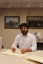 Photo of Zahoor looking through a box of items in the collection.