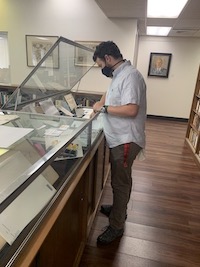 Photo of male student organizing items in an exhibit case.